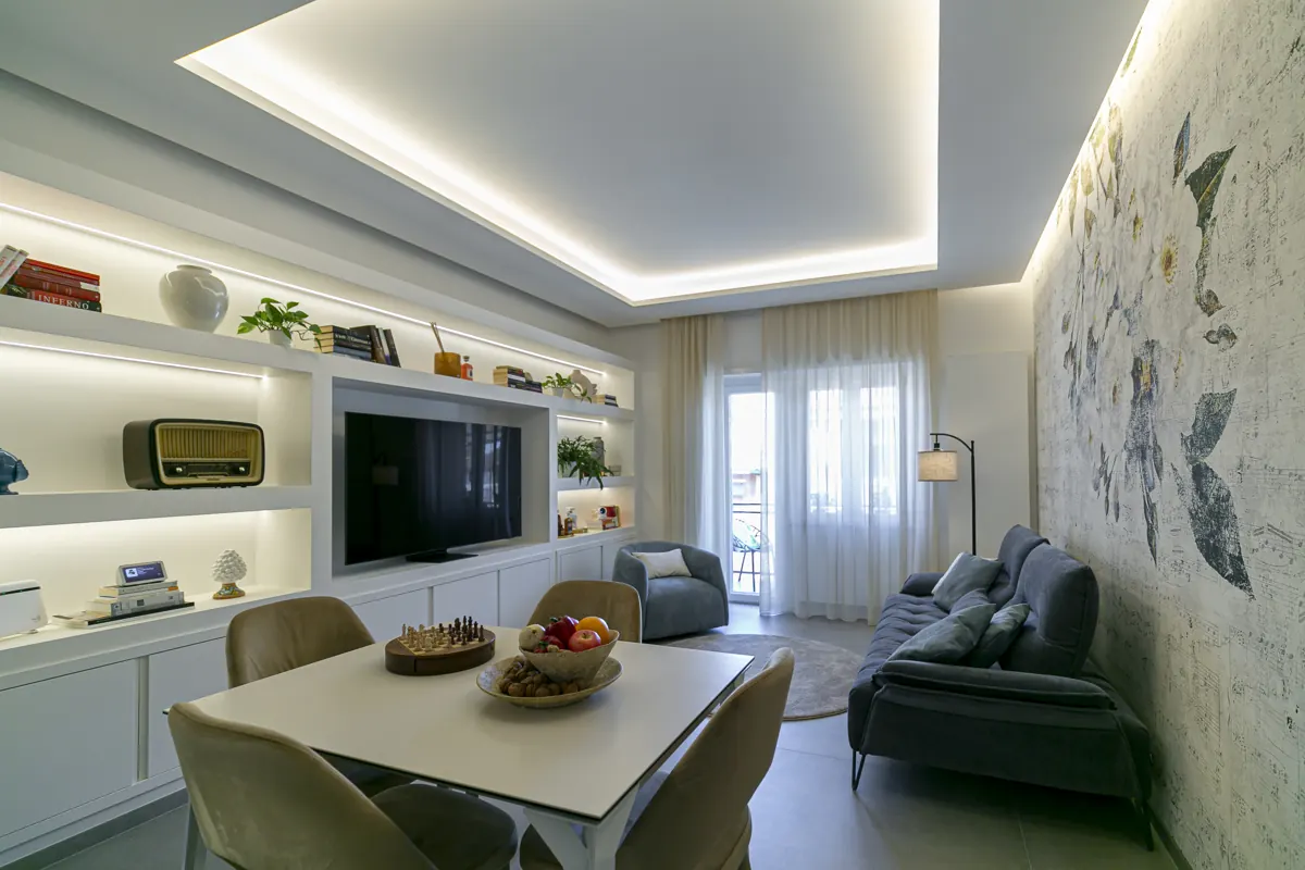 Soggiorno con libreria illuminata e parete decorativa